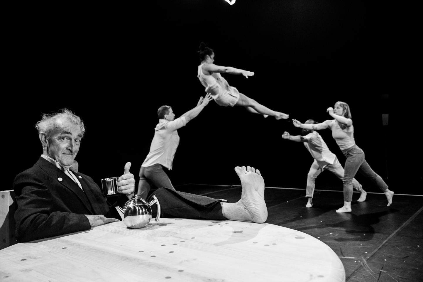 photo of acrobats flying through the air with a man at a table in the foreground